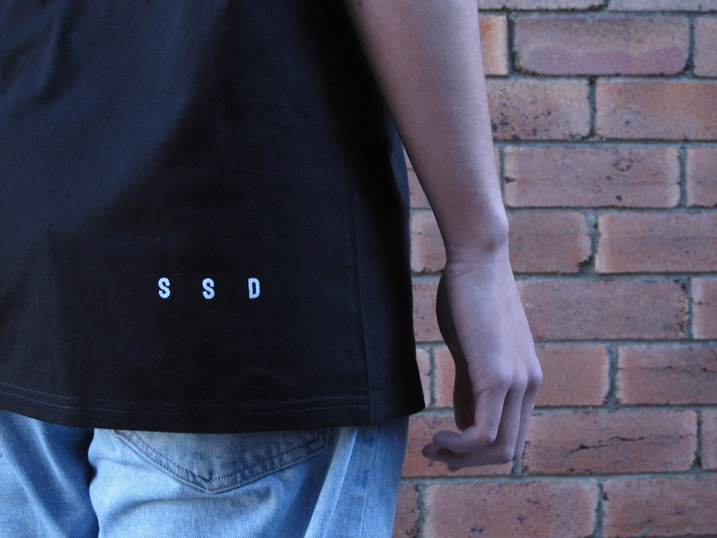 Our signature SSD right side print that represents Soul Submitted Designs. Positioned on bottom right of the tee shirt on back. Approx 1.5 cm in height and 8cm wide . White ink on black tee