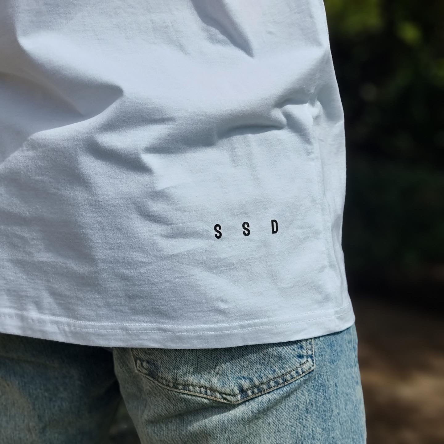 Right side bottom of shirt small black print SSD - acronym for Soul Submitted Designs.