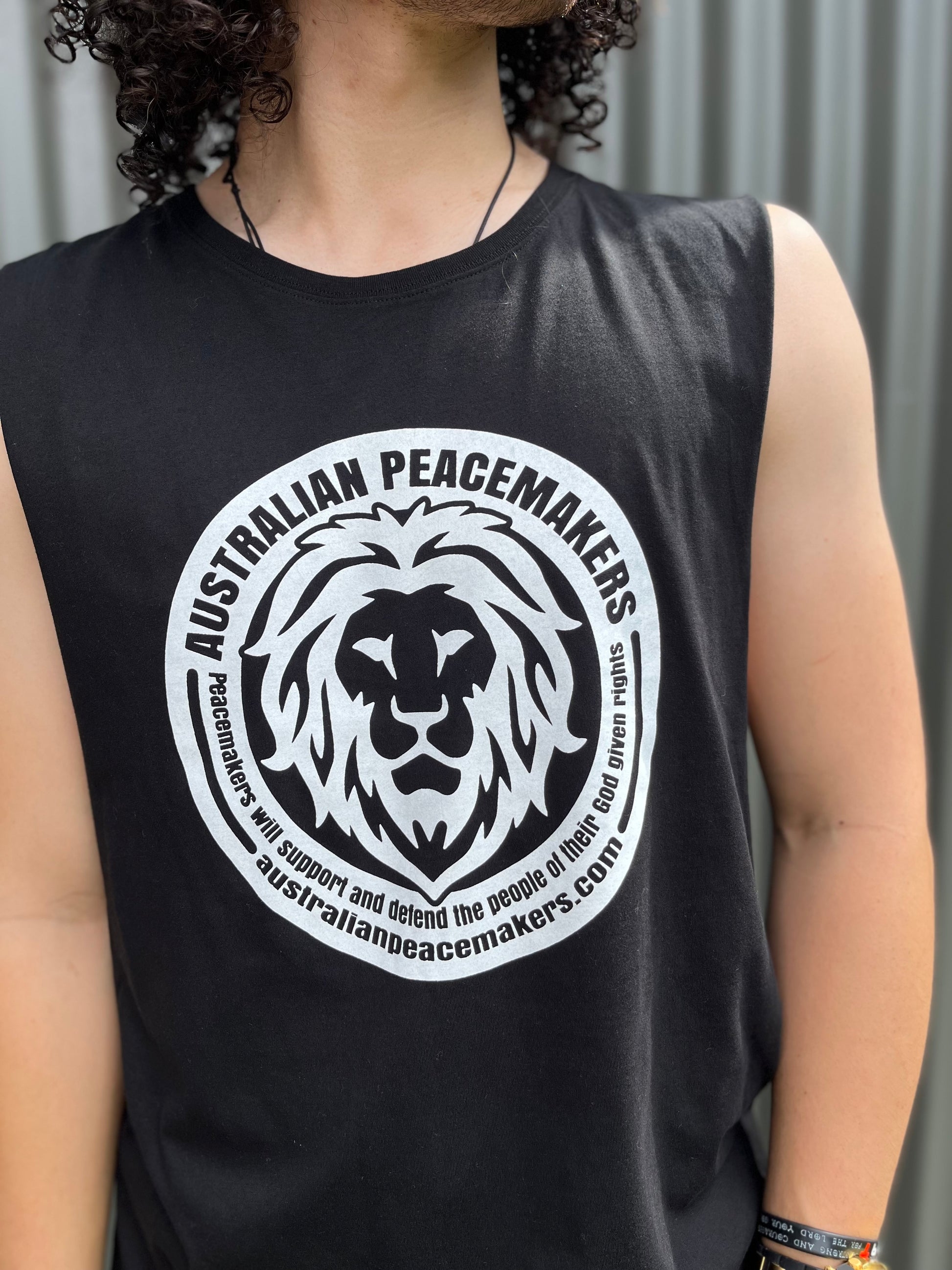 Black muscle top with white inked print on front. Print design - lion image with Australian Peacemakers quotation. Peacemakers will support and defend the people of their God given rights. BLANK back SIZES M to 2XL.