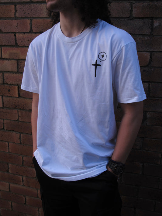 a male wearing a White T-shirt with a pocket print of cross symbol with a speech bubble with a love heart inside printed in black