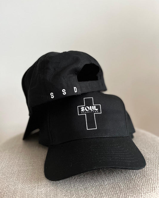 Pic of two black hats/ caps showing the front centred with logo Soul SUbmitted Designs in white vinyl. The other with SSD in capitals as an acronym for Soul Submitted Designs on back left. 
