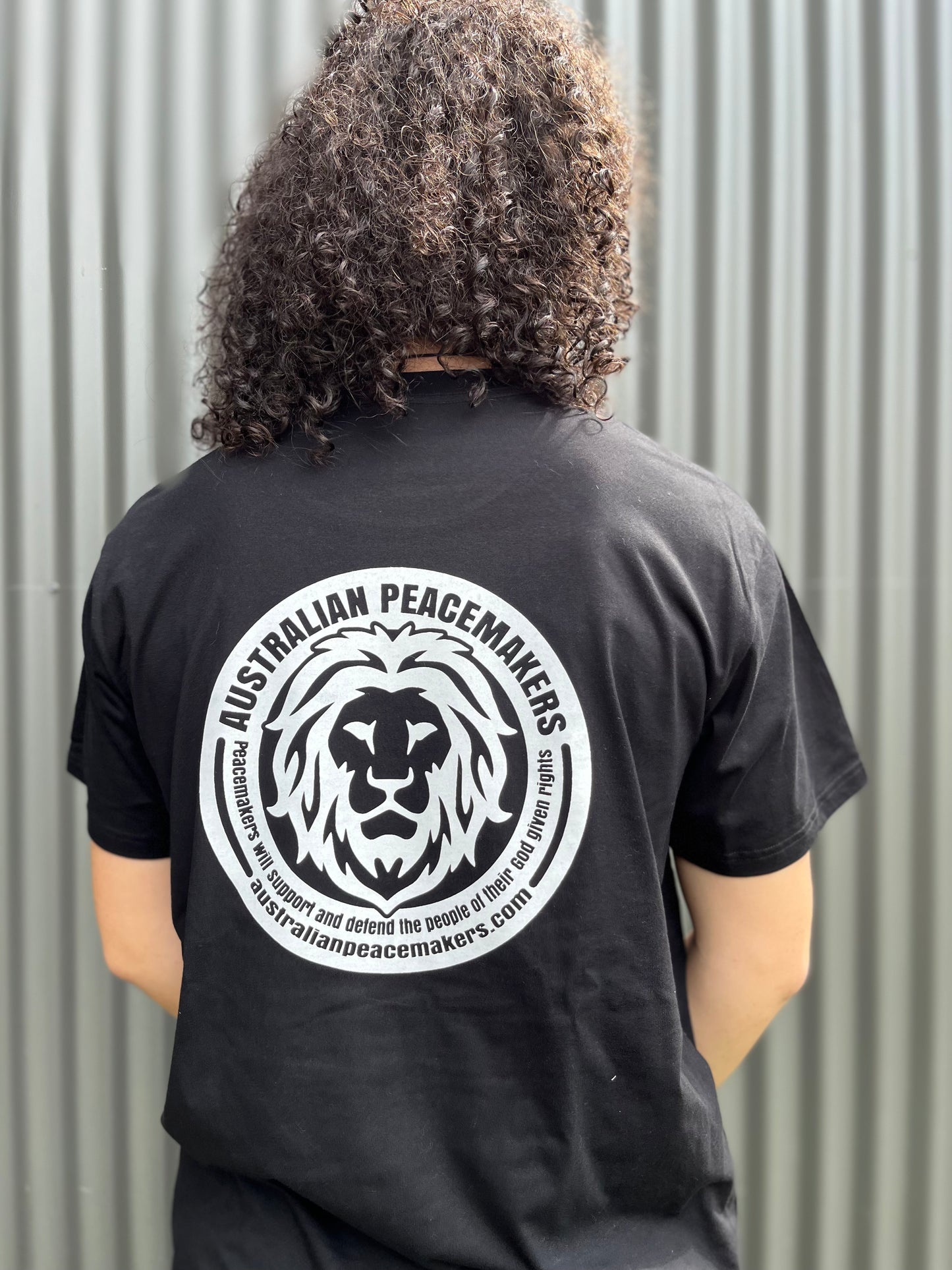 Black tee with blank front. Back print with Australian Peace Maker lion face image and statement of peacemakers. TEXT - Peacemakers will support and defend the people of their God given rights. 