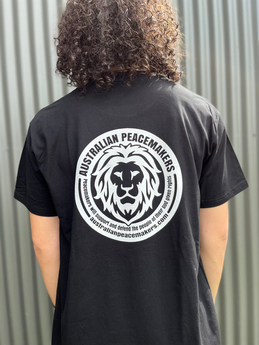 Black tee with blank front. Back white ink print with Australian Peace Maker lion face image and statement of peacemakers. TEXT - Peacemakers will support and defend the people of their God given rights.