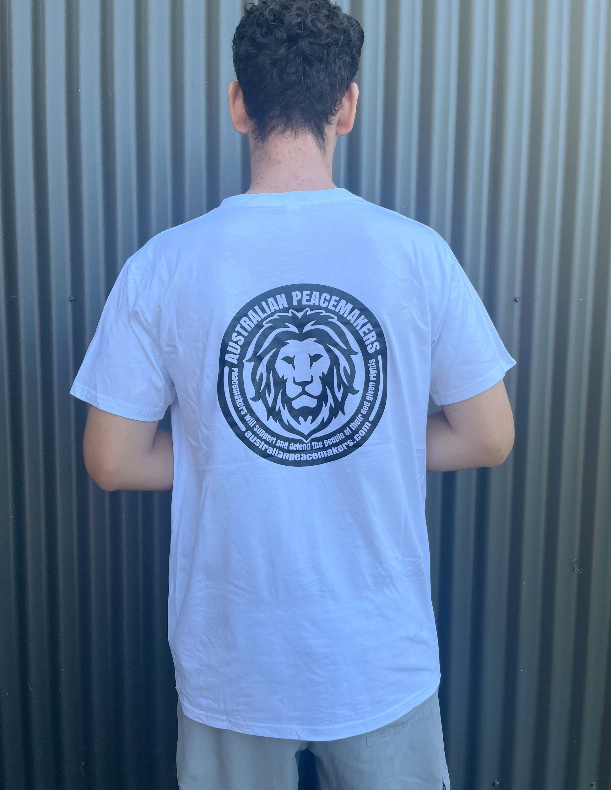 White tee with blank front. Back Black ink print with Australian Peace Maker lion face image and statement of peacemakers. TEXT - Peacemakers will support and defend the people of their God given rights.