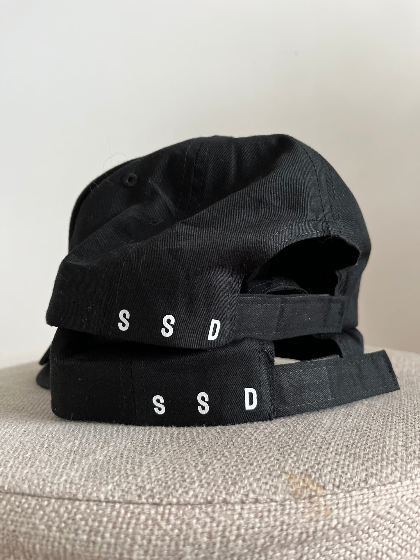 two hats/caps BLACAK - showing the SSD acronym as back left. 