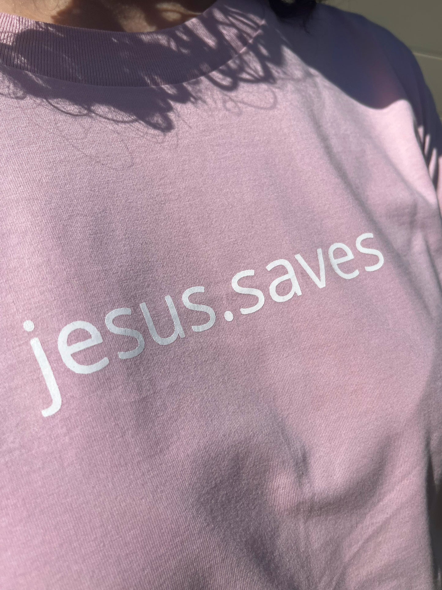 jesus.saves across the chest in stylish minimalistic font. Ink is white on pink shirt 